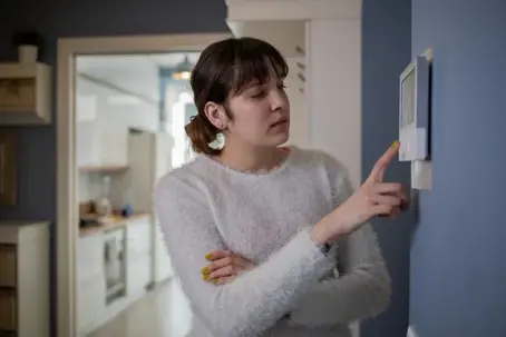 woman adjusting the thermostat